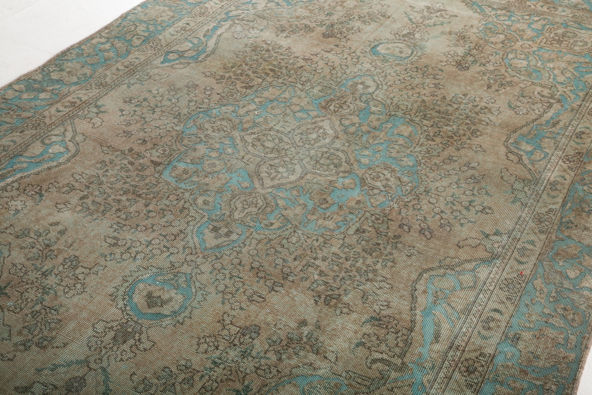 Tabriz rug with teal ornamental motifs across beige field and patterned corner