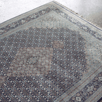 Light blue and navy border area rug with repeating medallion and diamond motifs.