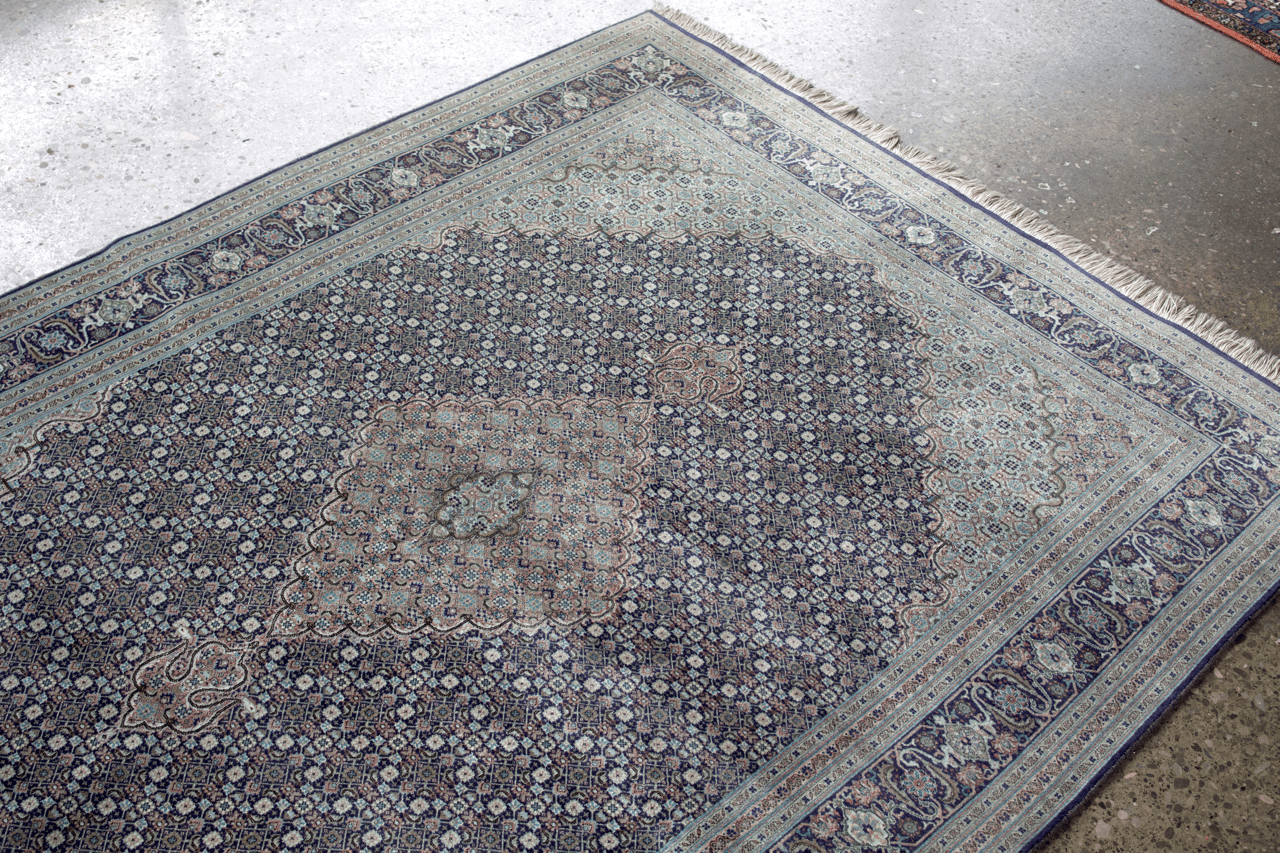 Light blue and navy border area rug with repeating medallion and diamond motifs.