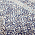 Blue and cream geometric Persian-style area rug with ornate medallion pattern close-up.