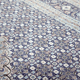 Blue and cream geometric Persian-style area rug with ornate medallion pattern close-up.
