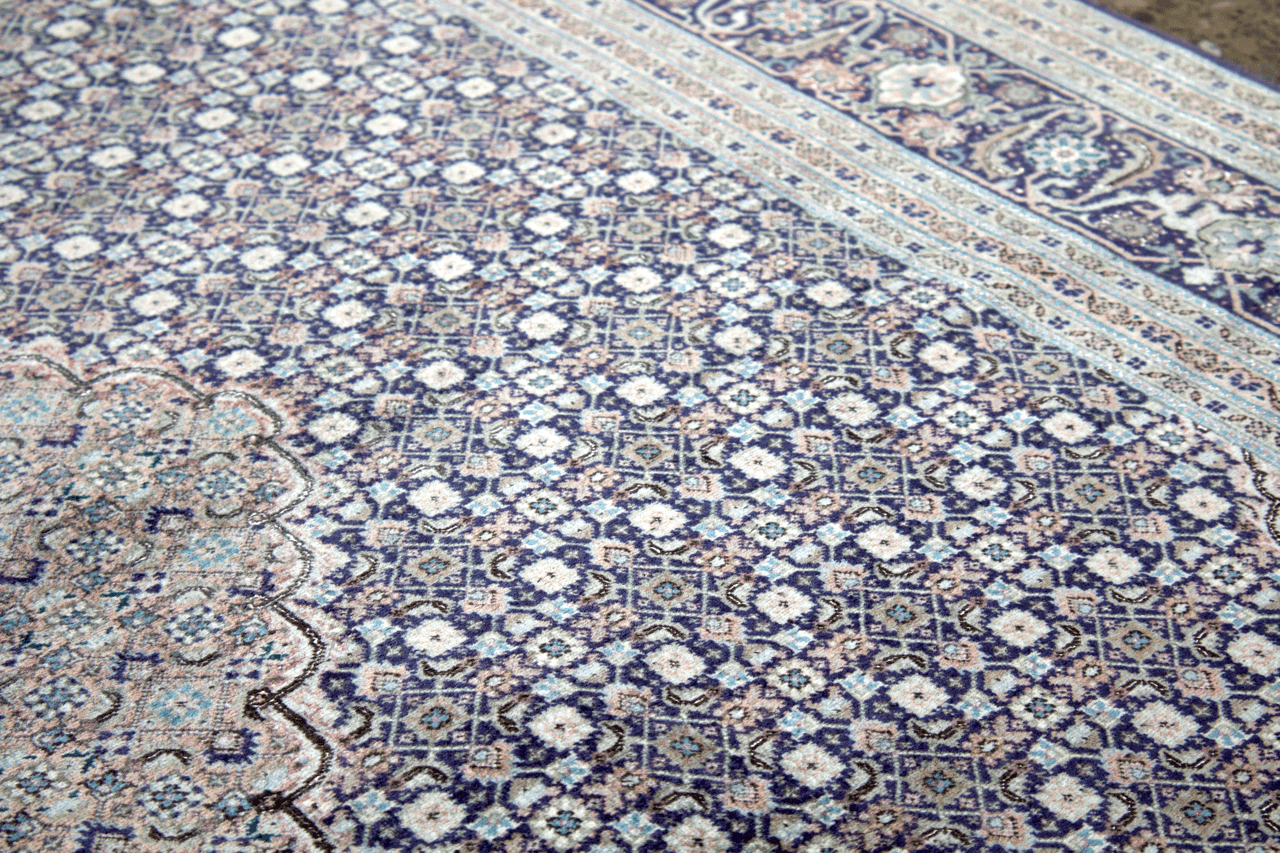Blue and cream geometric Persian-style area rug with ornate medallion pattern close-up.