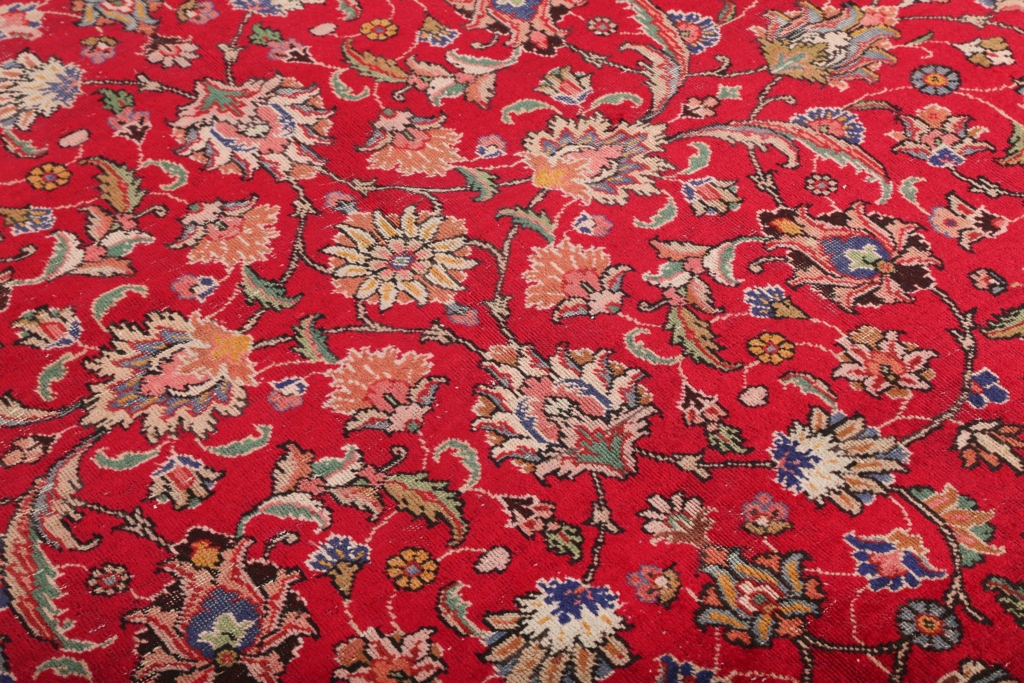 Close-up of red Persian rug surface with multicolor floral and vine motifs