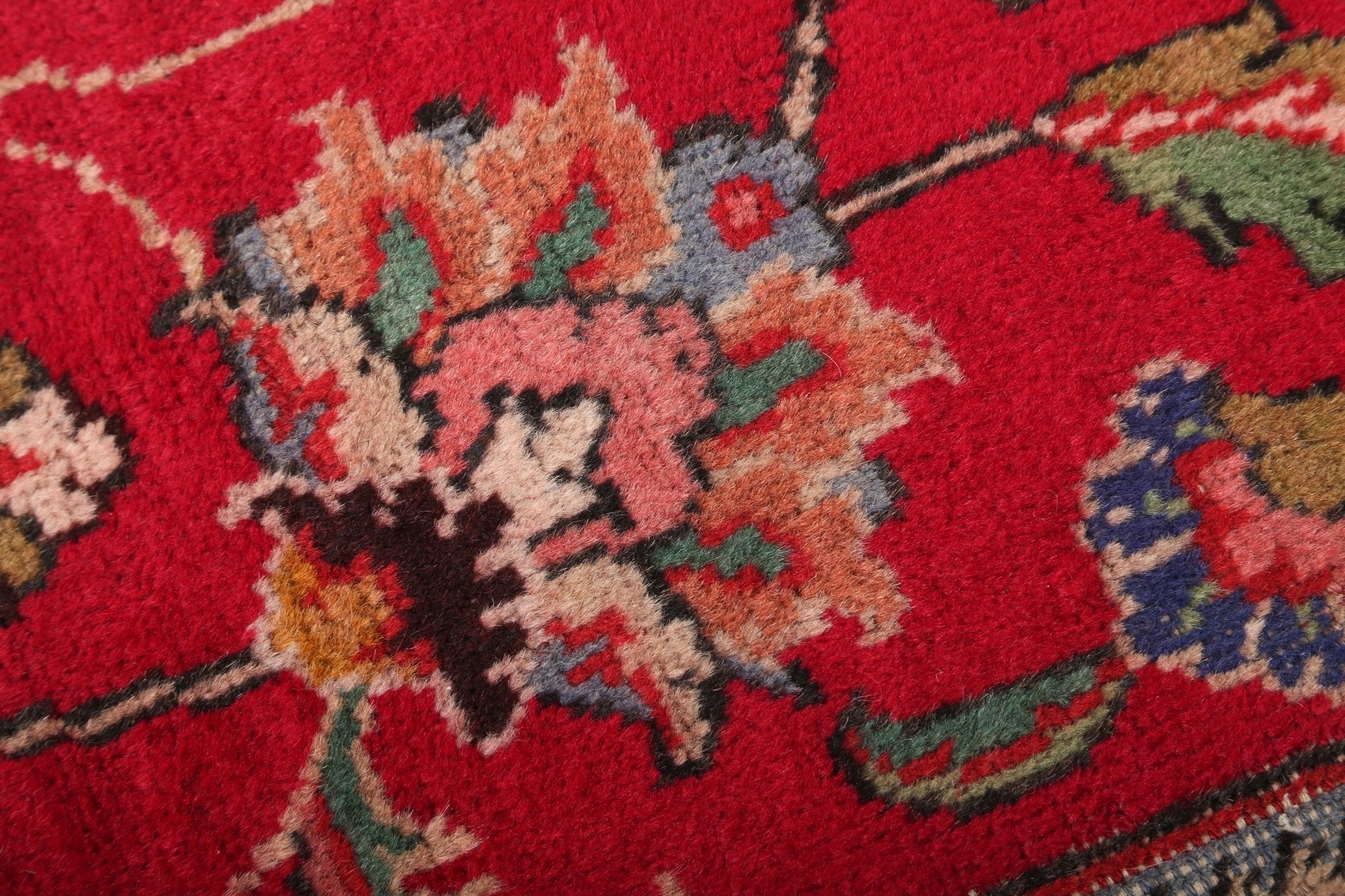 Close-up of red rug floral motif with multicolor accents and textured pile