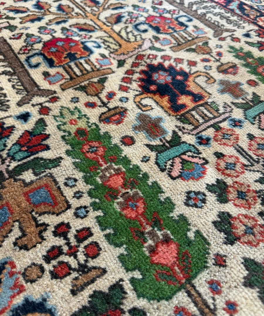 Persian Tabriz rug close-up with cream background, green vines, and red floral clusters