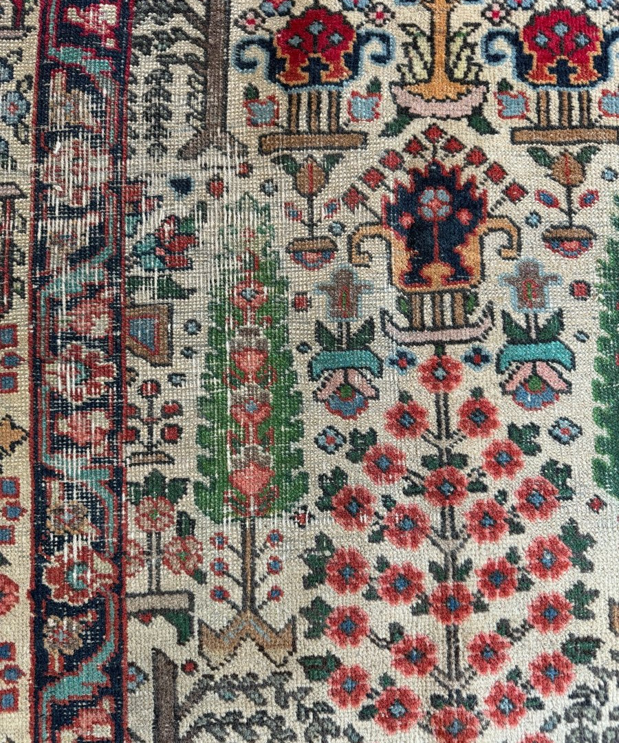 Persian Tabriz rug close-up showing cream ground, red rosettes, blue medallions, and vines