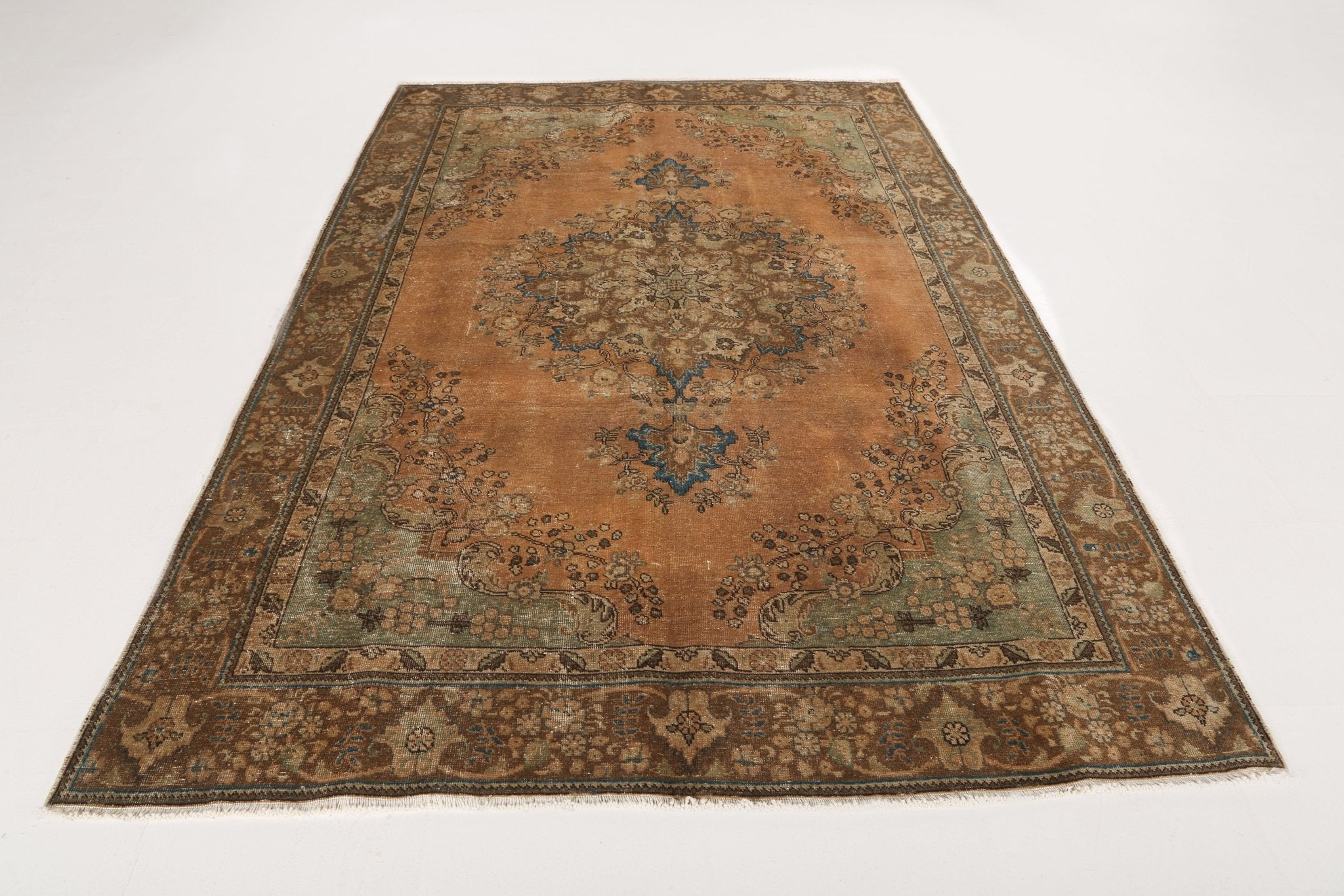 Persian rug with rust field, central medallion, teal floral details, and wide border