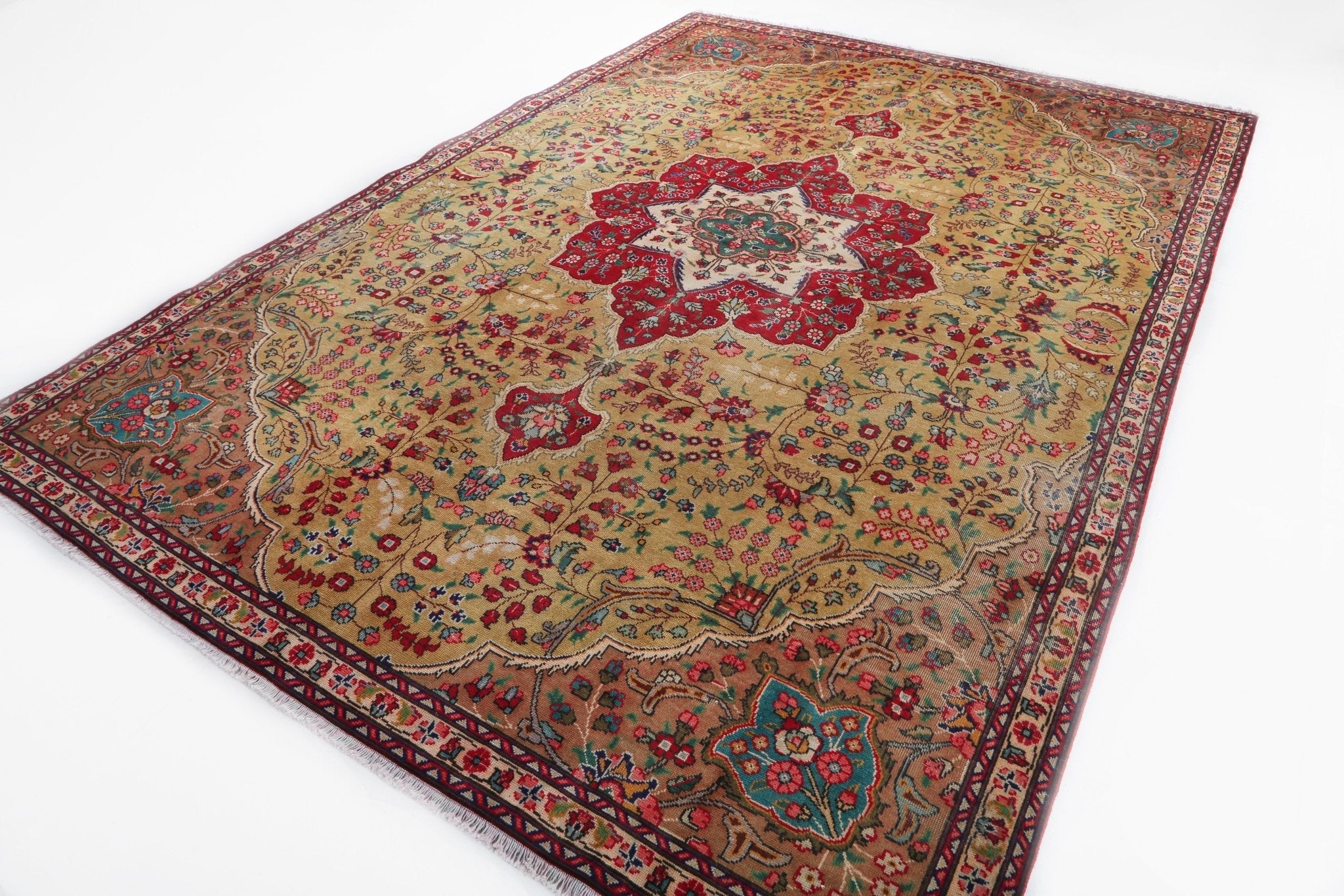 Persian Tabriz style rug laid flat, cream field with red central medallion and teal details.