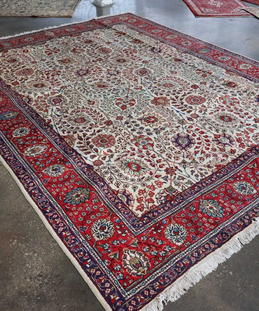 Persian-style area rug with cream, red, and navy floral medallion border and fringe.