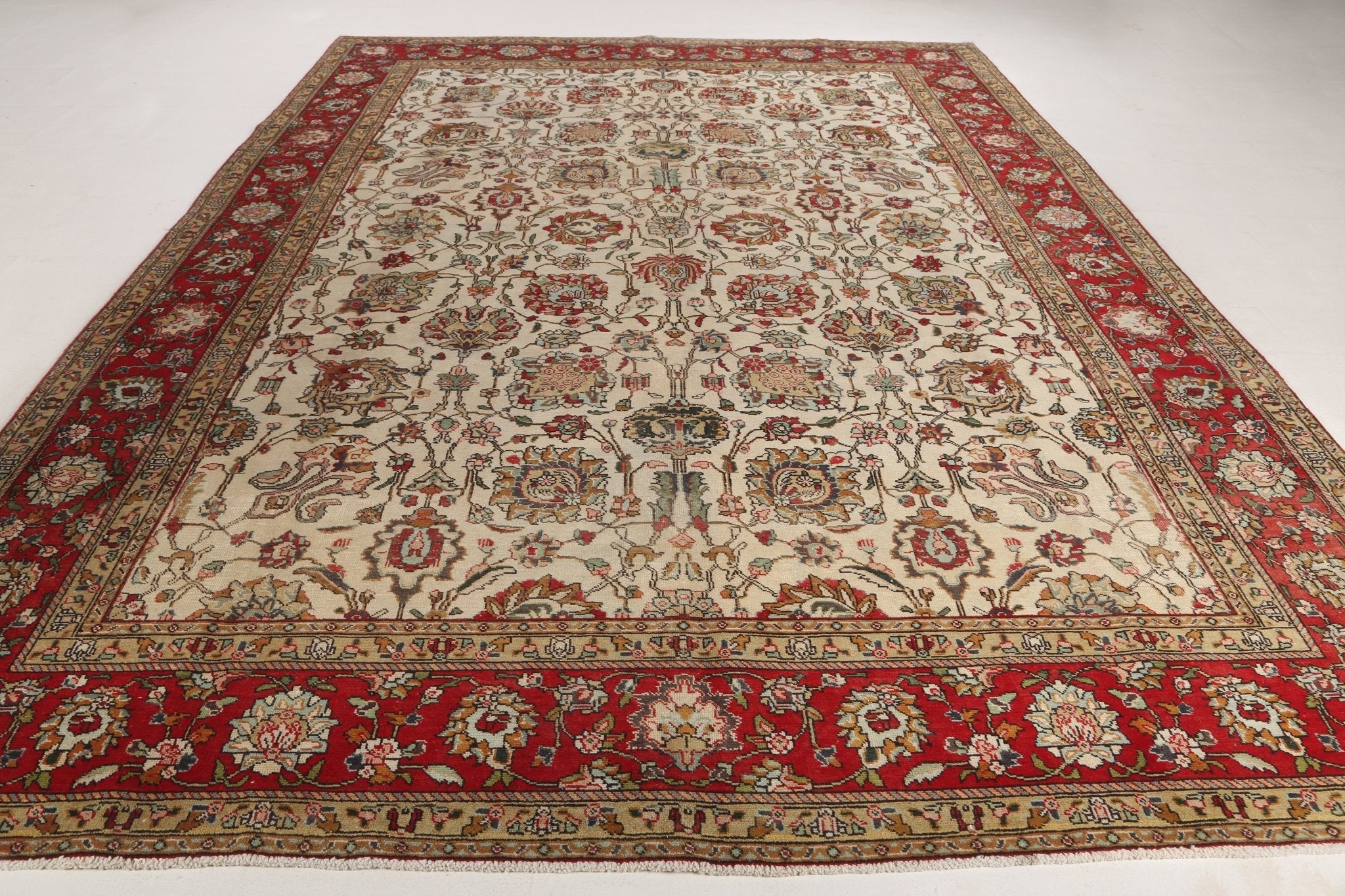 Persian-style Tabriz rug with cream center and wide red border with floral bands