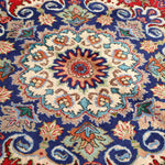 Persian Tabriz rug with navy medallion design on red-blue ground and floral accents