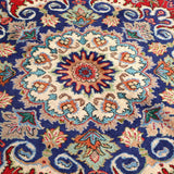 Persian Tabriz rug with navy medallion design on red-blue ground and floral accents