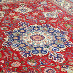 Persian Tabriz rug top view with red background and large blue rosette medallion