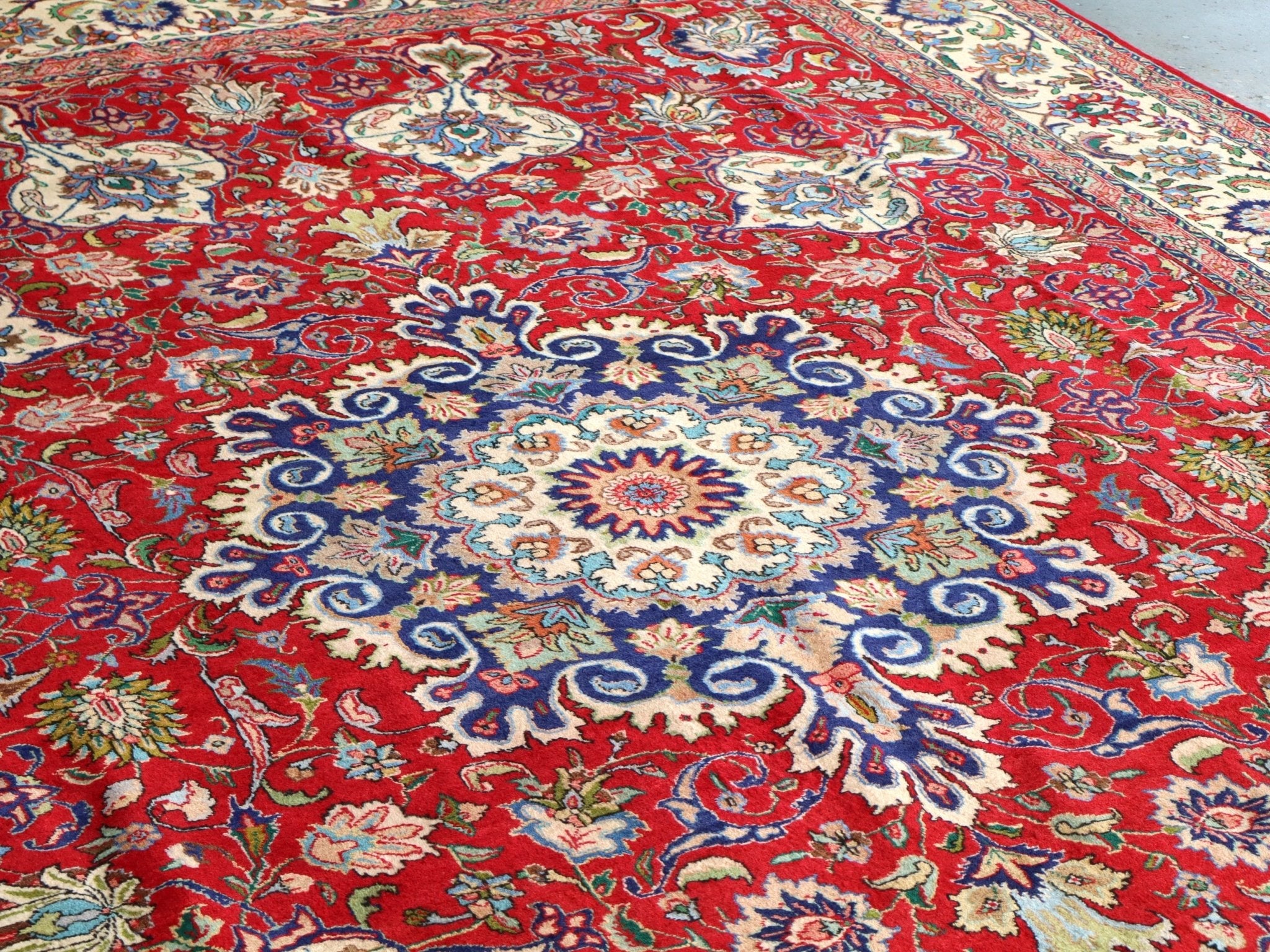 Persian Tabriz rug top view with red background and large blue rosette medallion