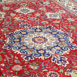 Persian Tabriz rug top view with red background and large blue rosette medallion