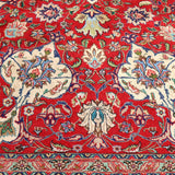 Persian Tabriz rug close-up of red field, blue motifs, and cream scrollwork border