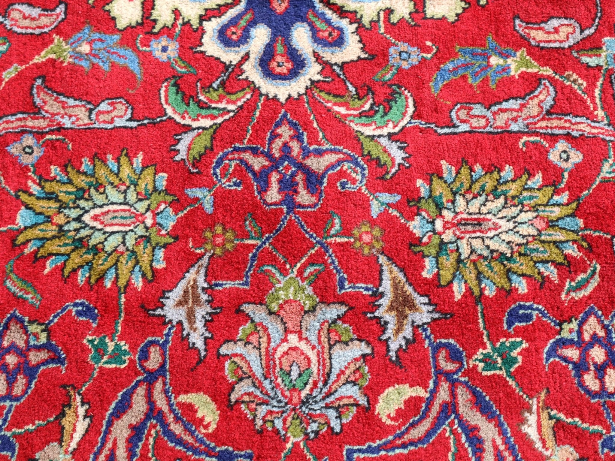 Persian Tabriz rug with red field and blue motifs, cream and green accents