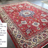 Persian Tabriz rug on floor with red center medallion and cream border motifs