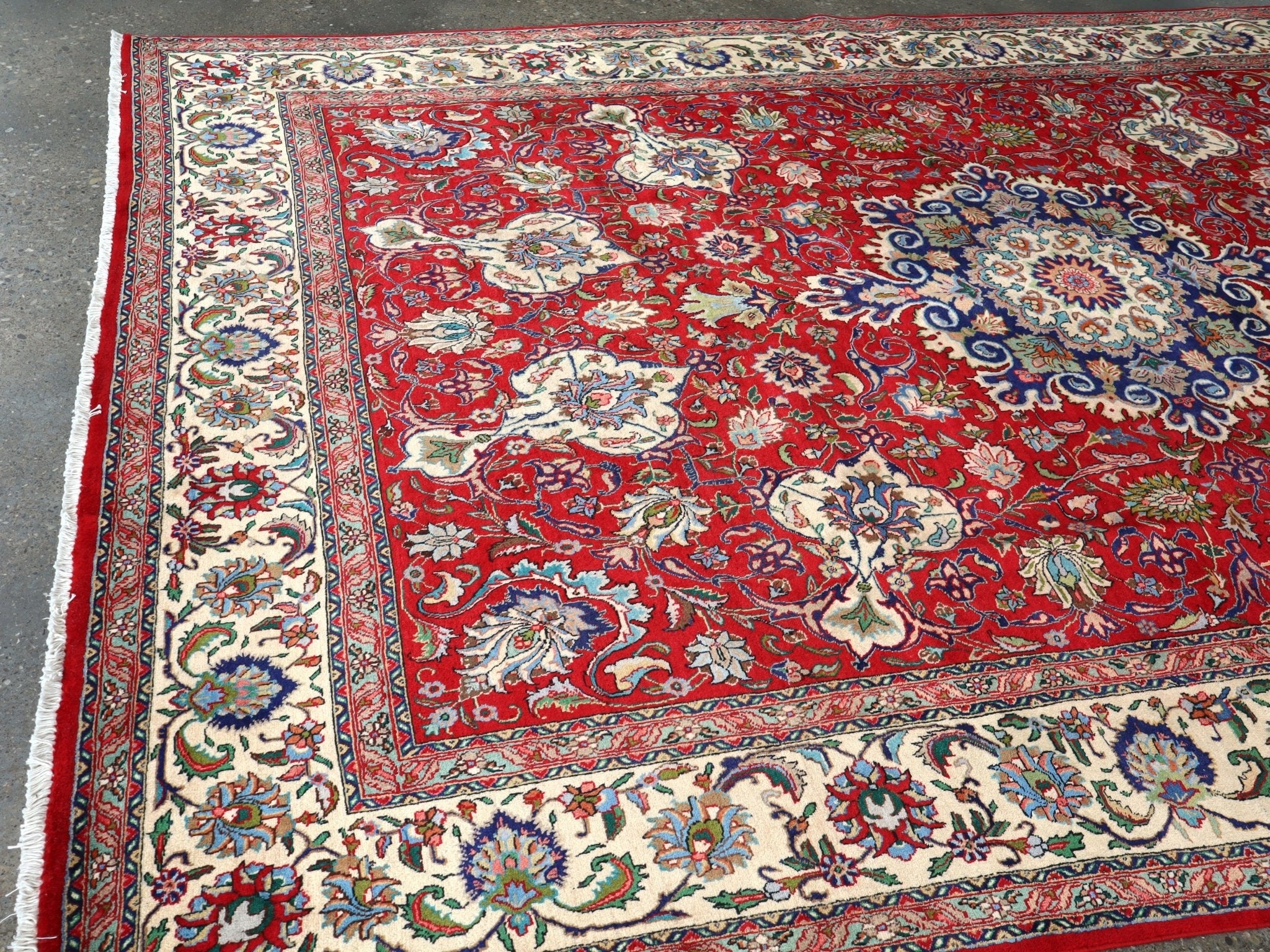 Persian Tabriz rug corner view, red field with cream border and blue floral details