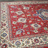 Persian Tabriz rug corner view, red field with cream border and blue floral details