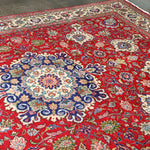 Persian Tabriz rug featuring red main field with ornate floral and rosette patterns