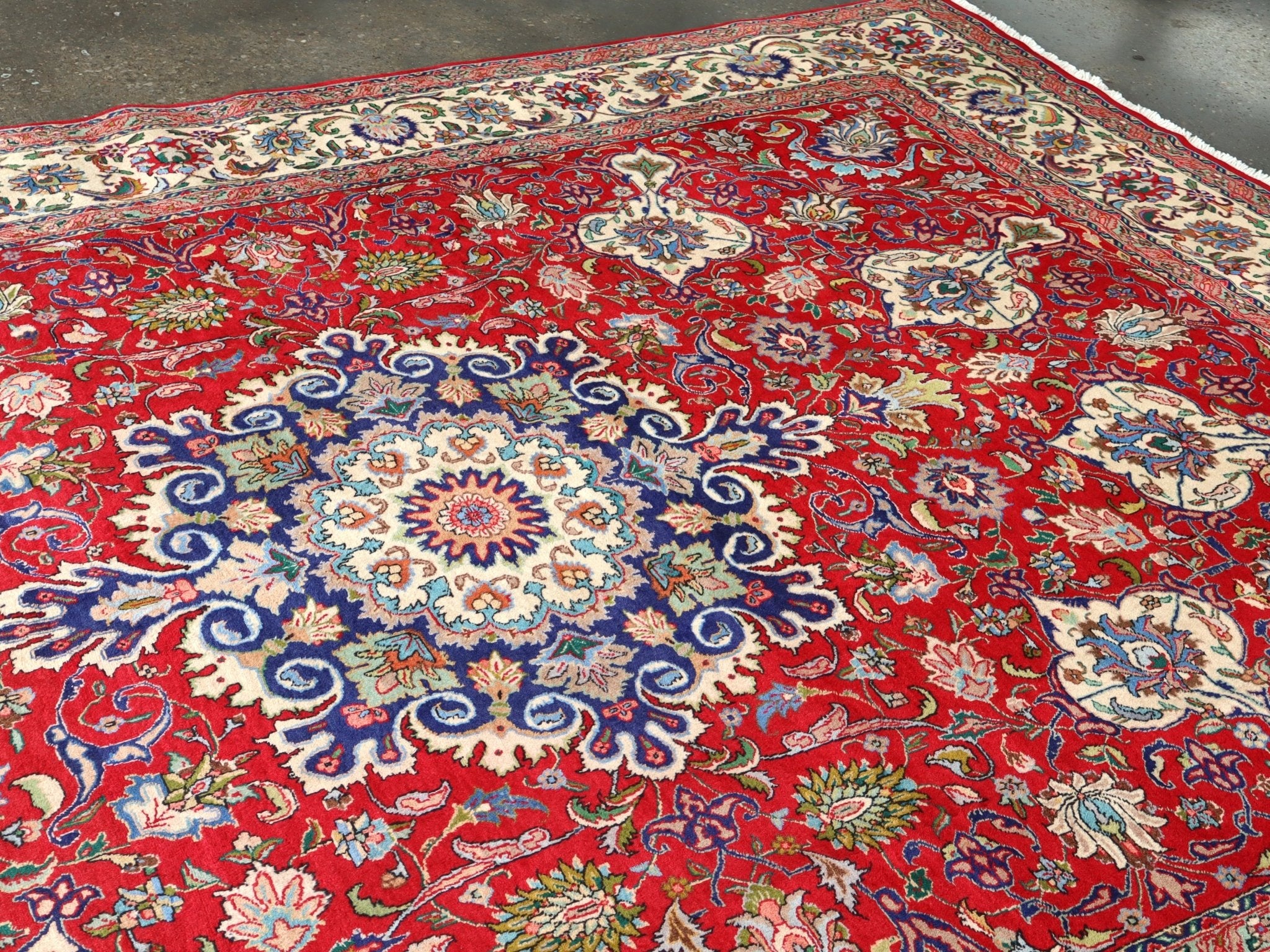 Persian Tabriz rug featuring red main field with ornate floral and rosette patterns