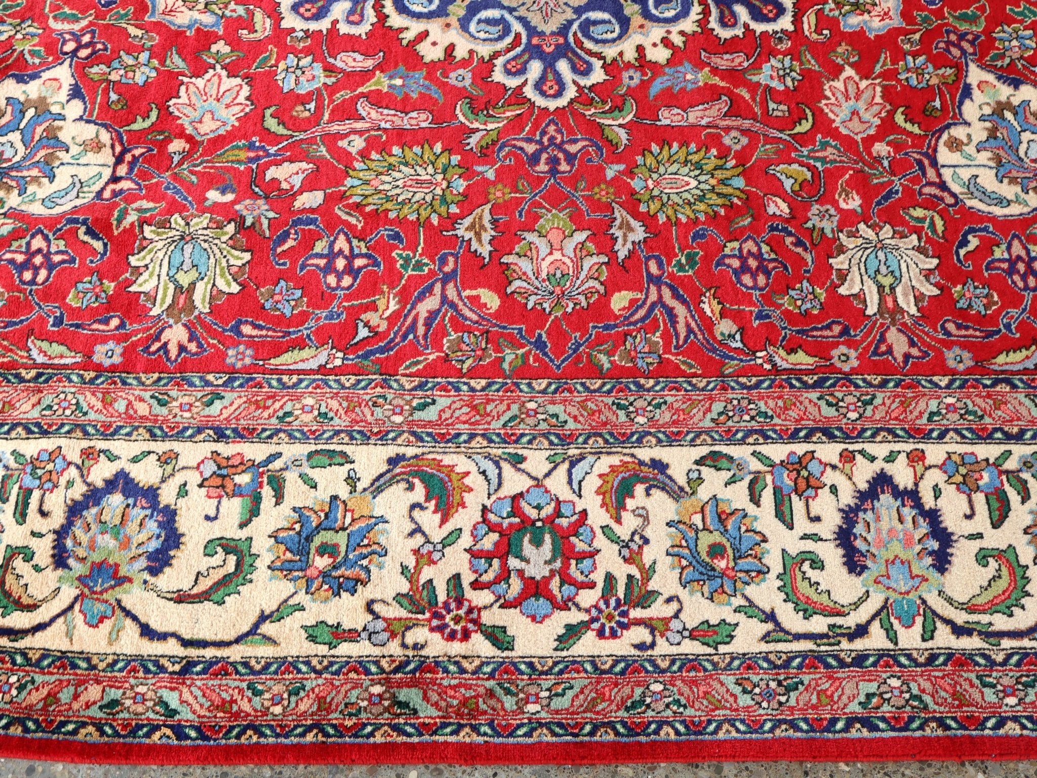 Persian Tabriz rug border detail with red background, blue outlines, and cream highlights