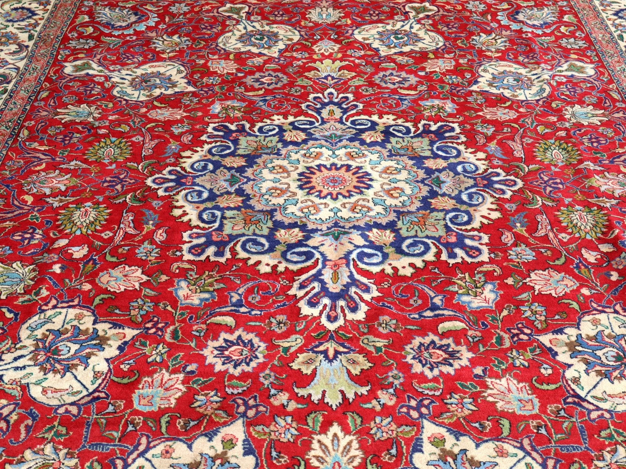 Persian Tabriz rug with centered medallion, red with cream border and blue floral accents