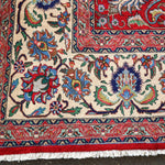 Persian Tabriz rug border close-up with red edges, cream ground, and colorful floral vines