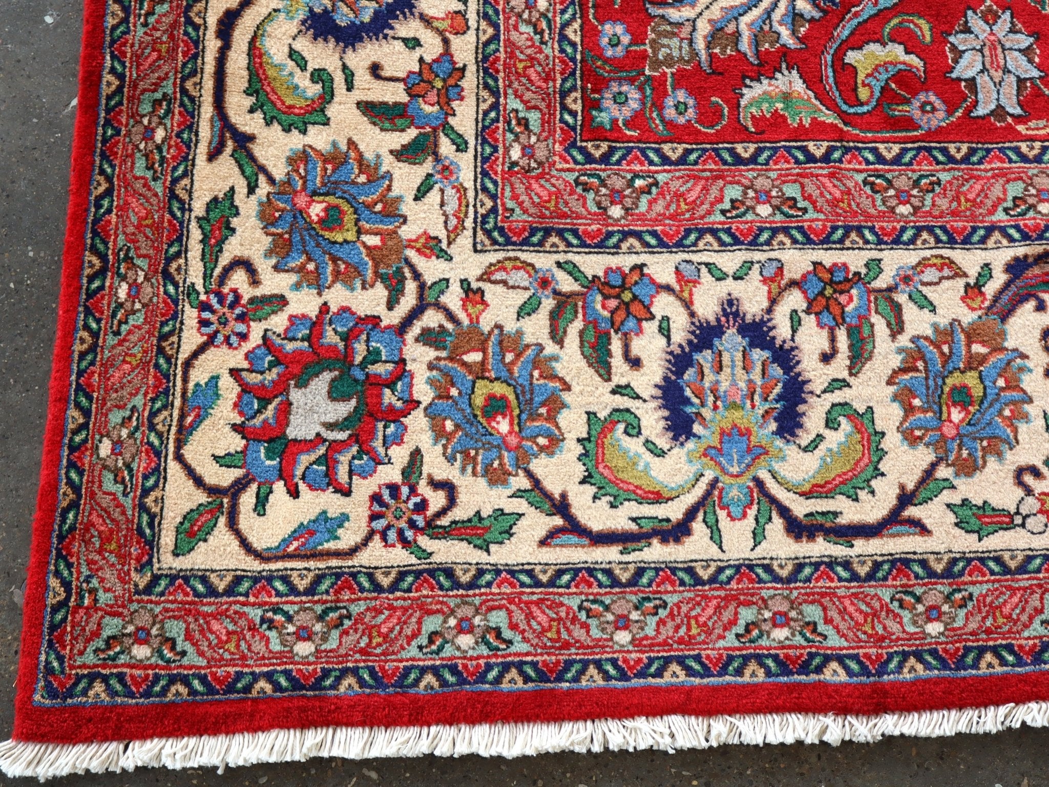 Persian Tabriz rug border close-up with red edges, cream ground, and colorful floral vines