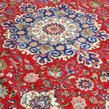Persian Tabriz rug with red field, blue floral medallion, and detailed curving motifs