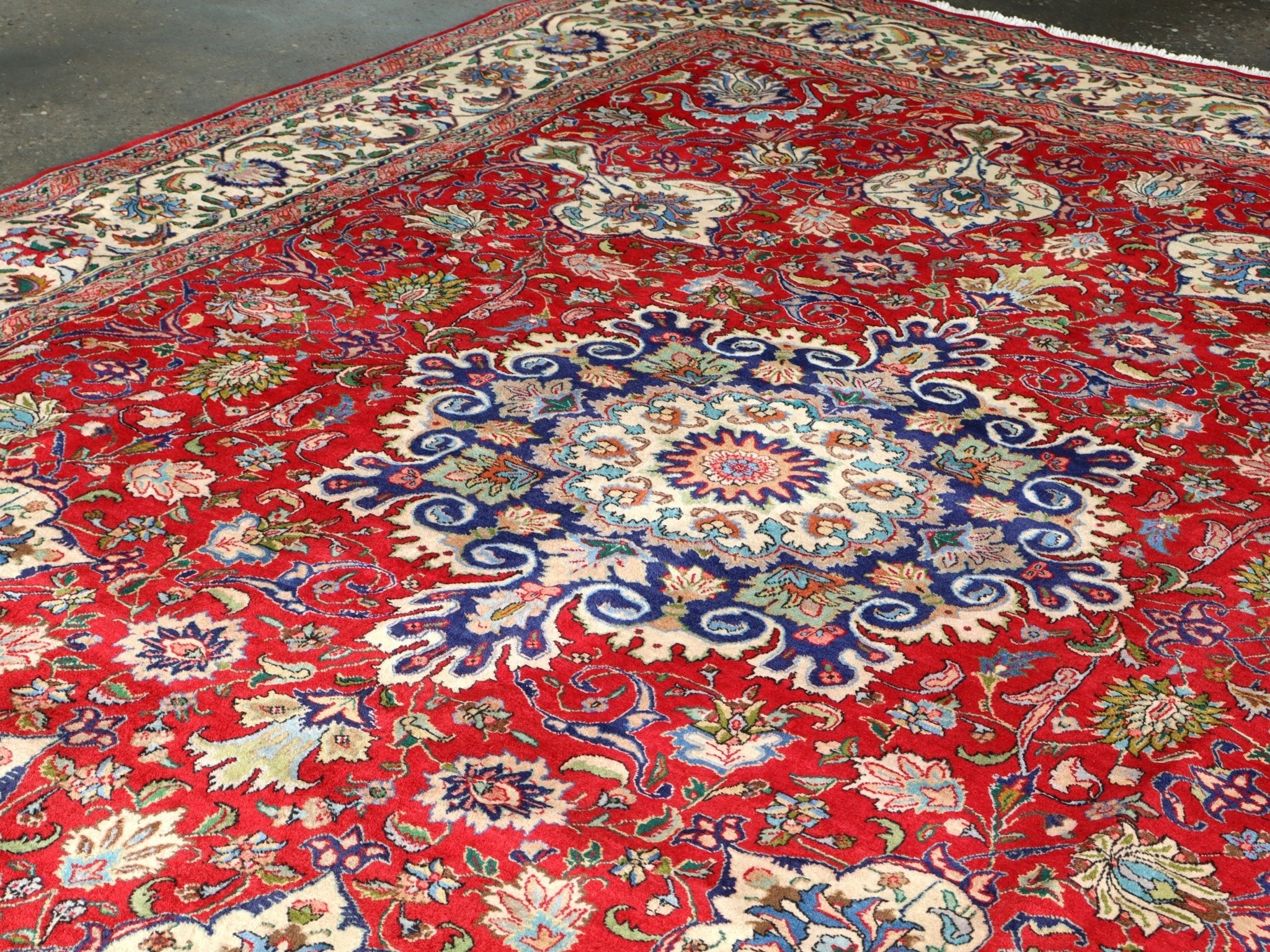 Persian Tabriz rug with red base and large central blue medallion surrounded by florals