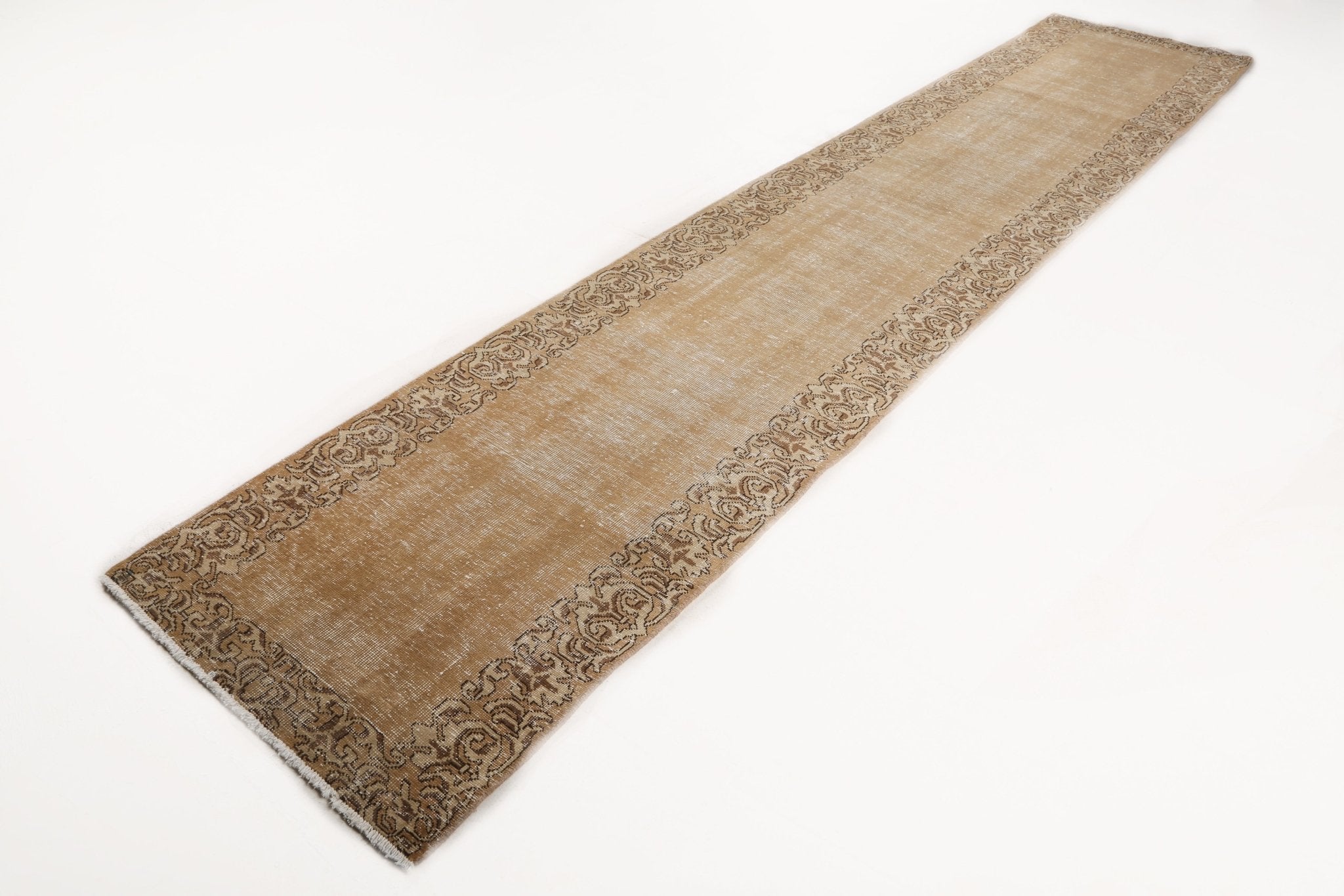 Tan runner rug with dark ornamental border and repeating corner motif design