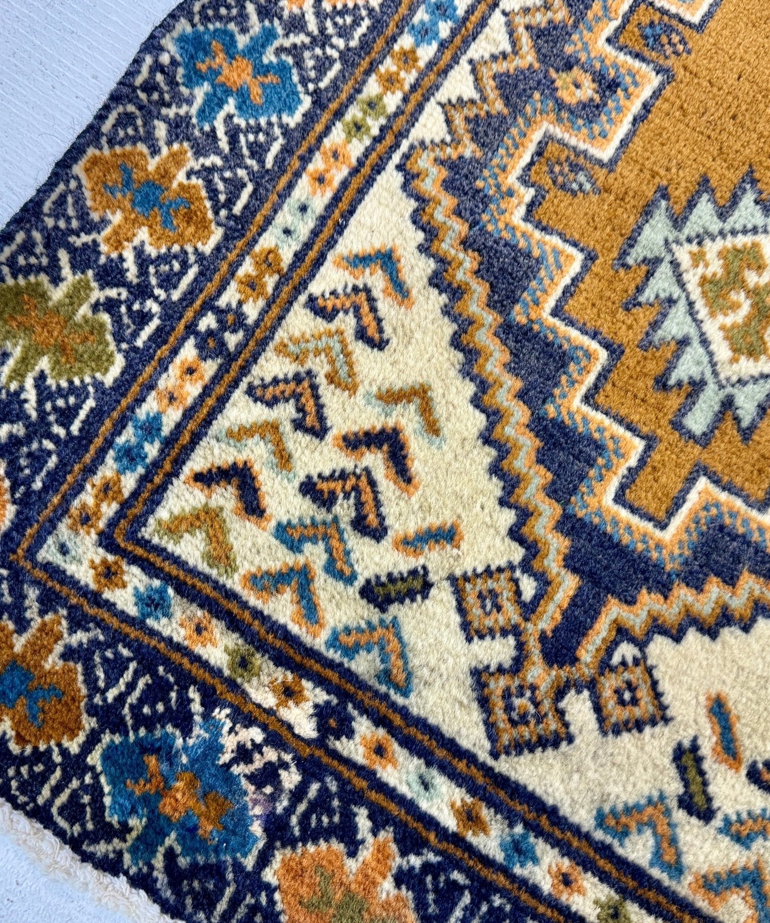 Turkmen rug corner with navy field, cream zigzags, and small floral diamond motifs