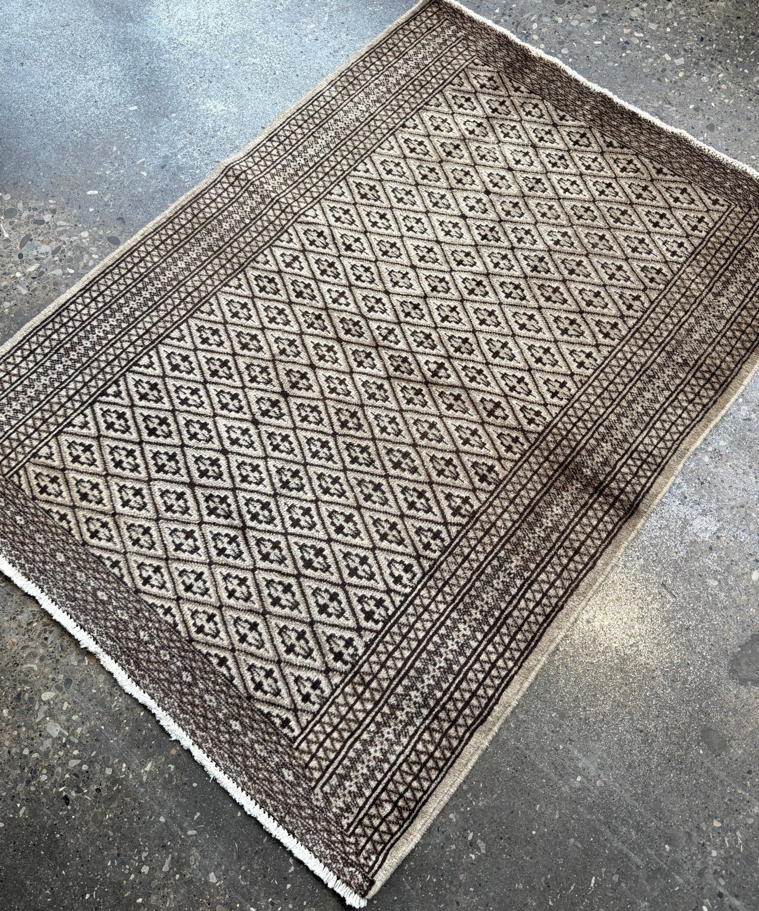 Square rug with central lattice pattern, dark border, and fringed corners