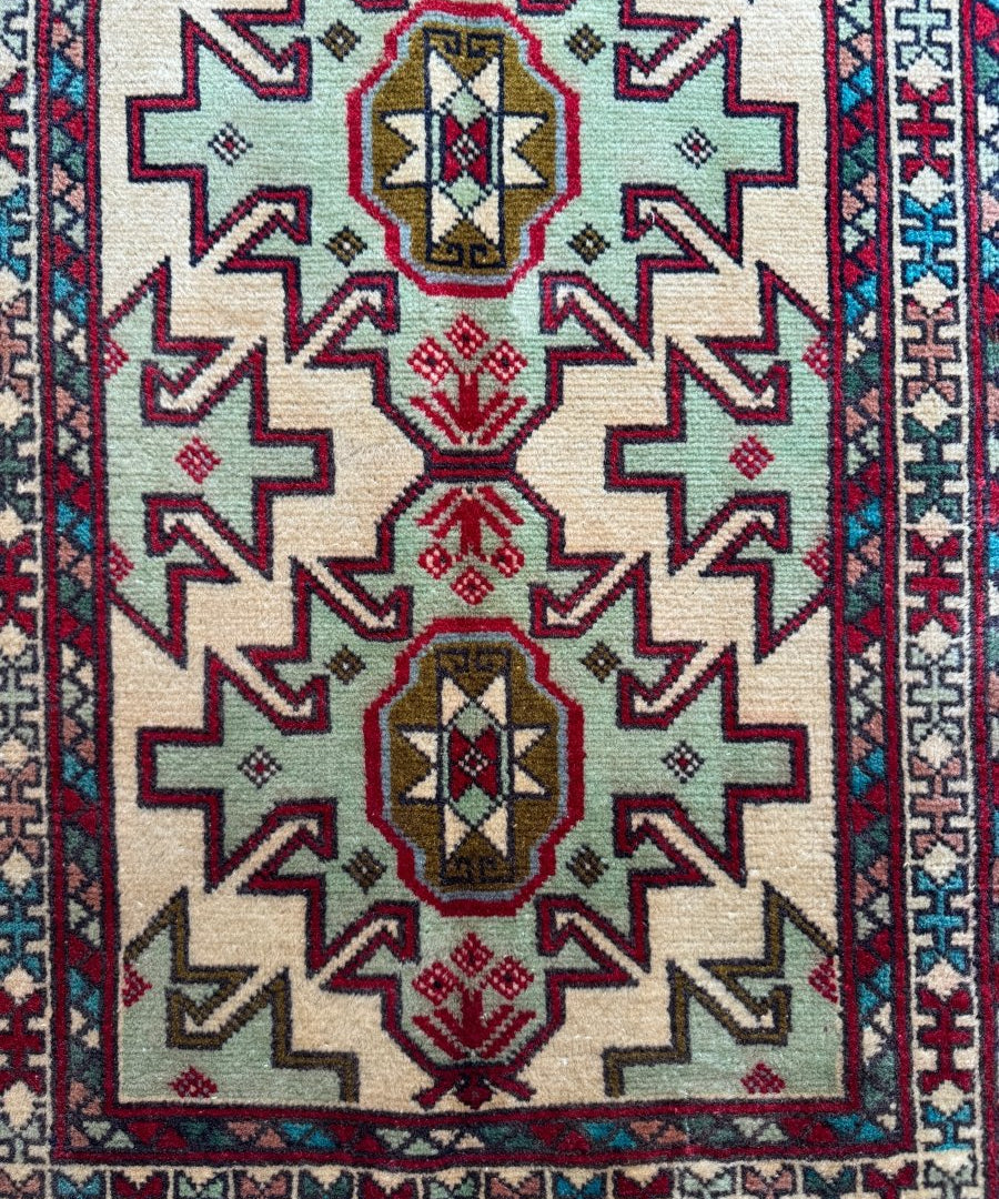 Persian Turkomana rug close-up: cream field with red border and central diamond medallion