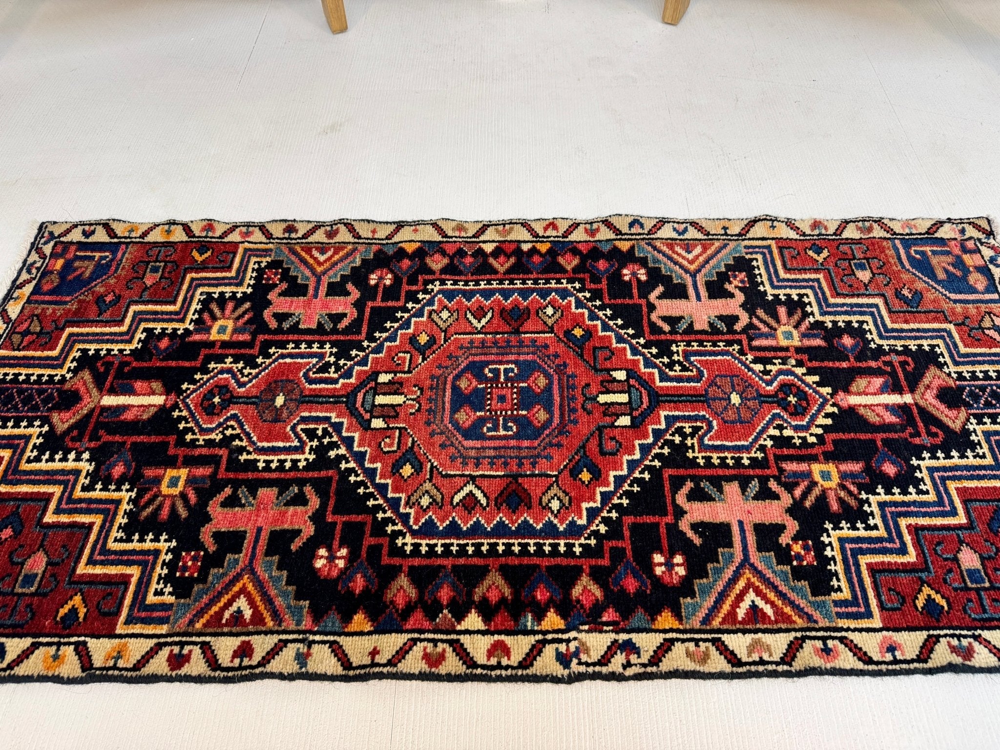 Narrow Persian-style runner rug with central medallion in red, navy, and cream