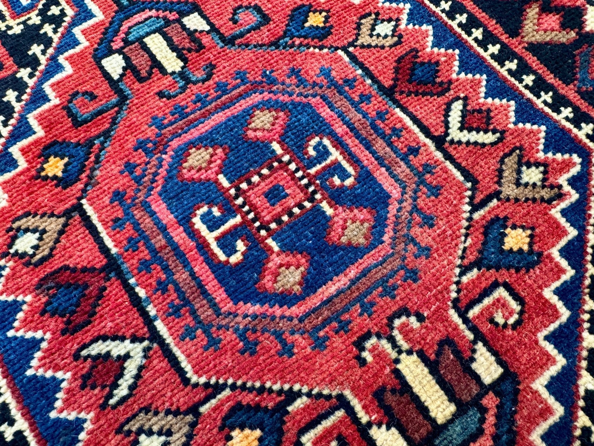 Persian-style runner rug with blue, red, and cream geometric medallion pattern
