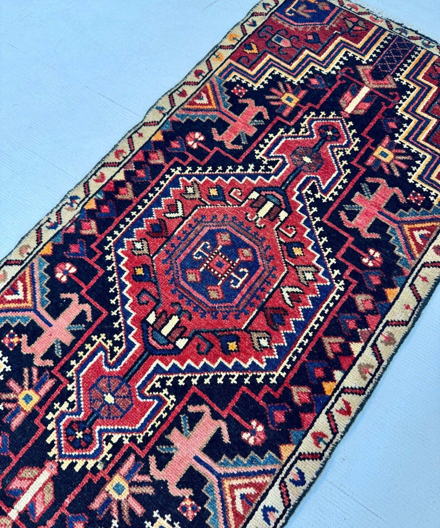 Persian-style runner rug angled view with navy, red, blue, and cream geometric pattern