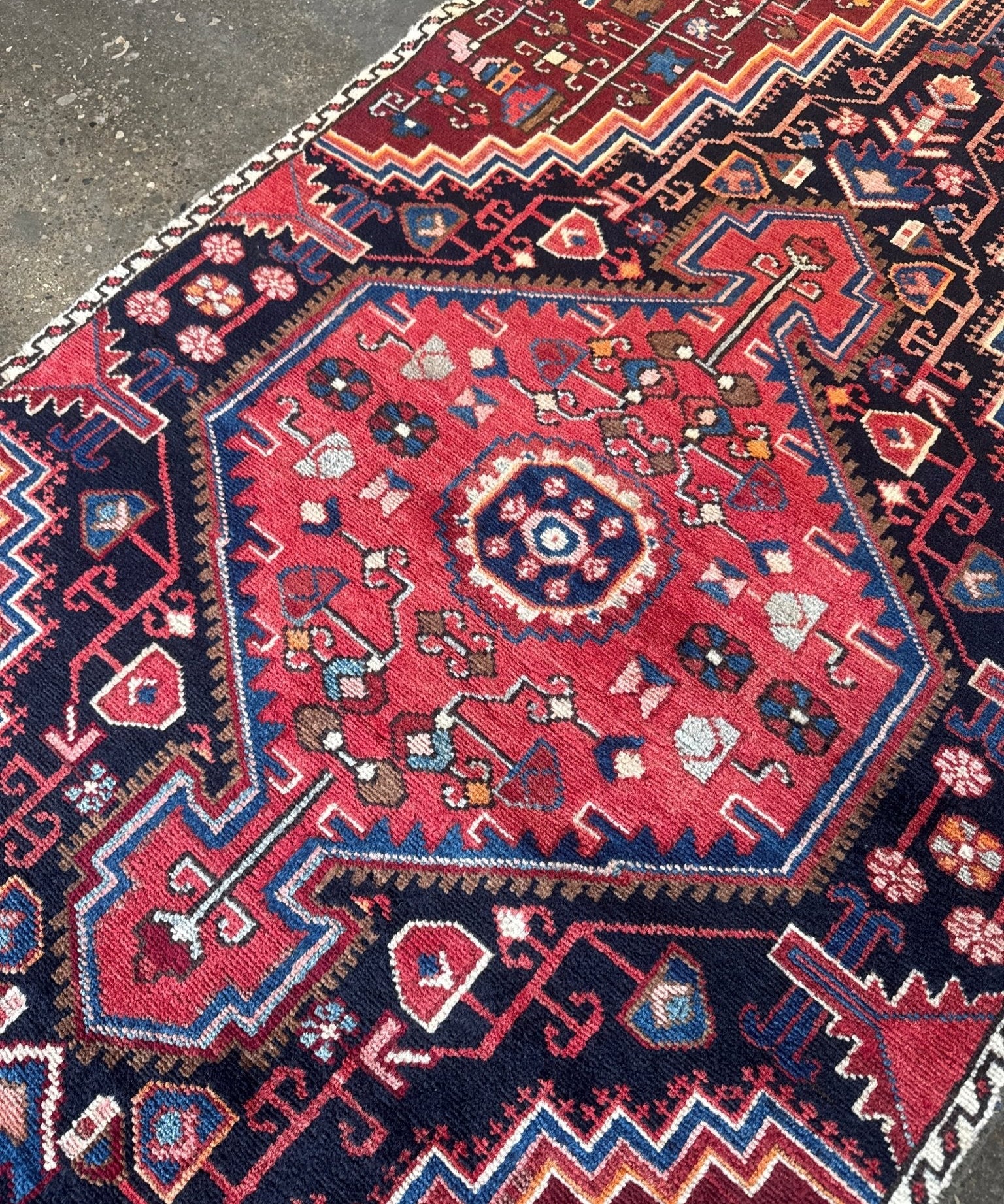 Persian rug close-up with central medallion and red, blue, cream ornamented borders.