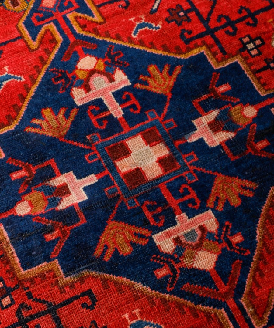 Tuyserkan Persian rug close-up: red, navy, and blue geometric motifs