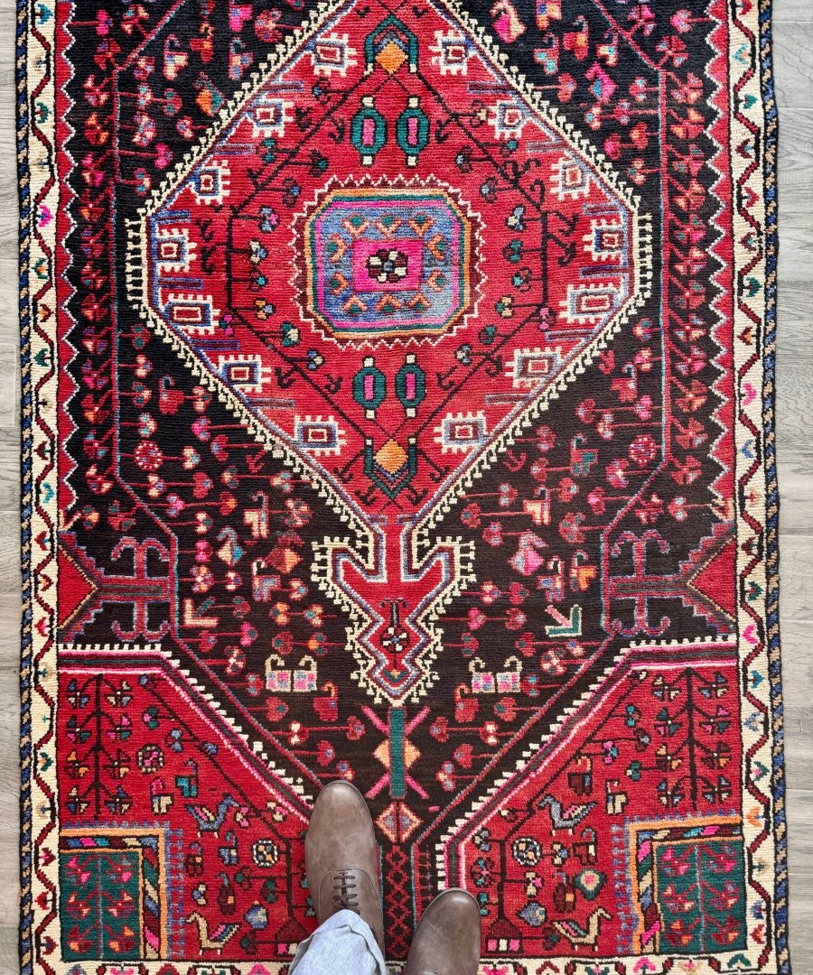 Persian-style rug with red center medallion, navy field, and cream geometric borders