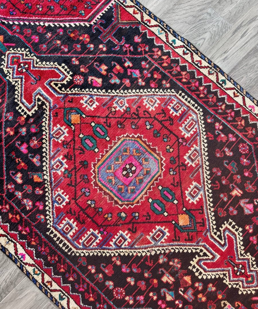Close-up of Persian-style rug pattern with red ground, navy details, and cream trim