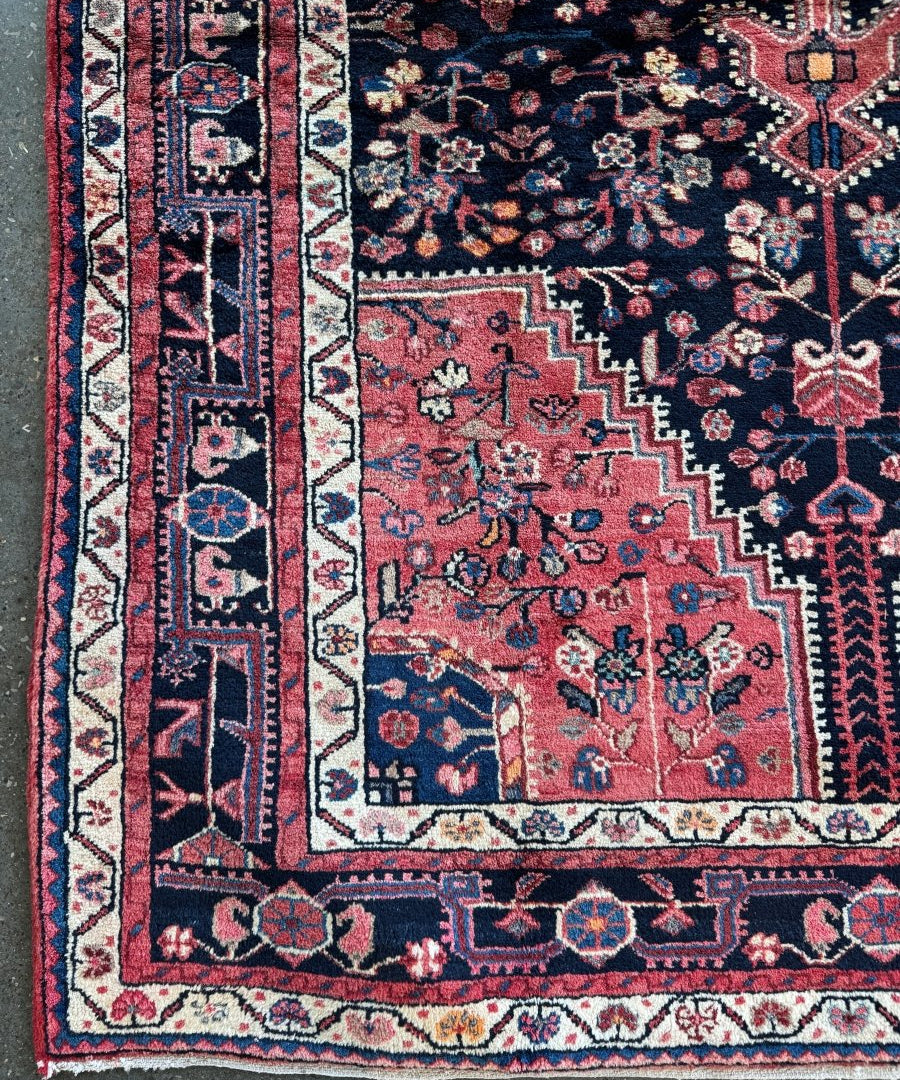 Persian-style rug detail showing navy ground with red motifs and a vertical cream border stripe