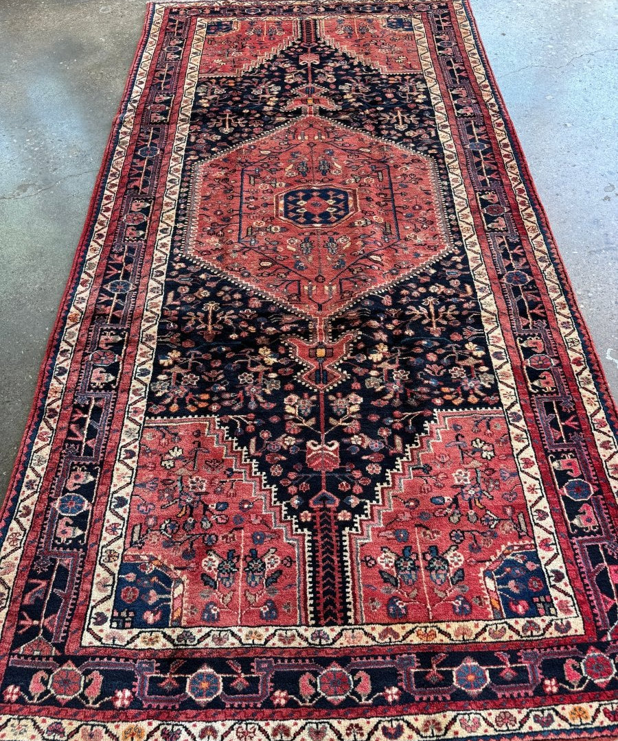 Persian-style area rug with central medallion, red and navy geometric pattern, cream border