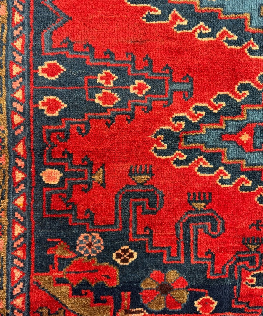 Persian Viss rug close-up of red field with navy corner motifs and small floral accents