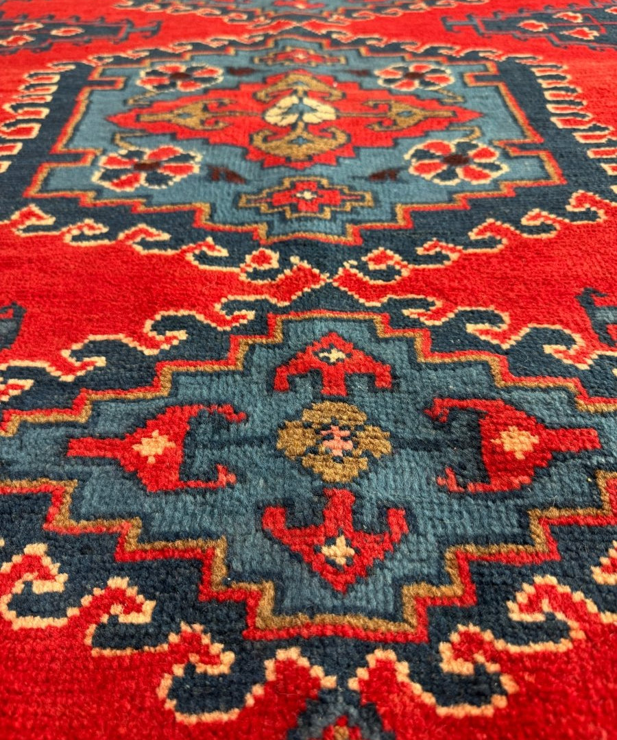 Persian Viss rug close-up with red pile texture, dark blue motifs, and central medallion