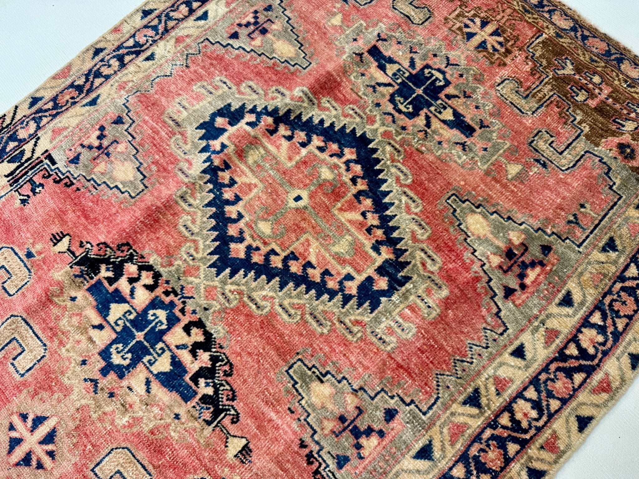 Close-up of Persian-style rug with red and navy diamond and stepped motifs.