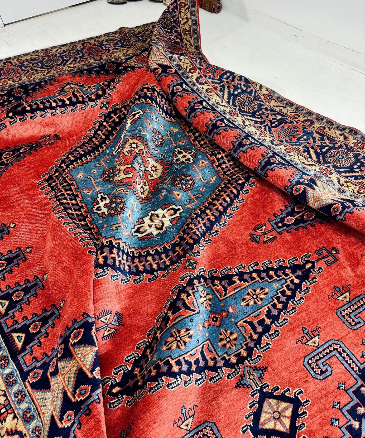 Persian Viss rug with red field, navy border, and blue floral medallion center