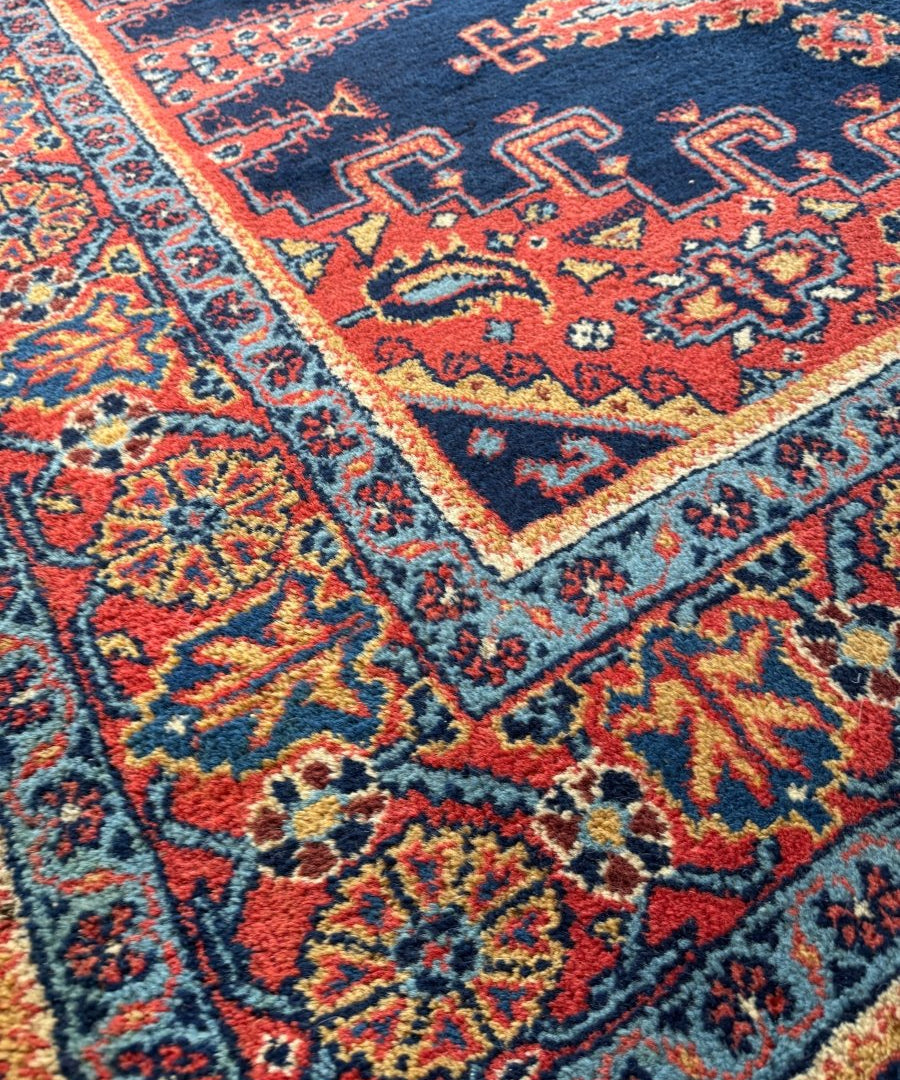 Navy Persian rug corner with red, blue, and orange geometric patterns